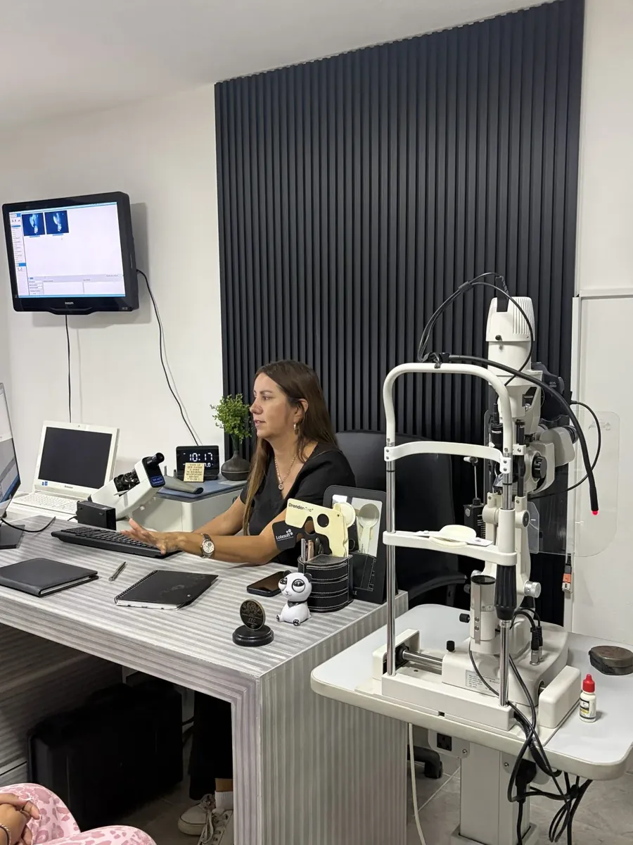 La doctora junto a la lámpara de hendidura en su consultorio